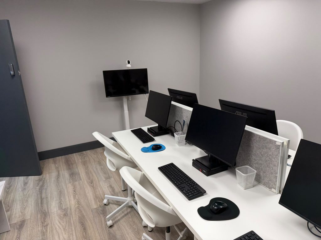 The Pefwil workspace in Dublin 11: a shared desk with monitors, white chairs and a wall screen for video calls